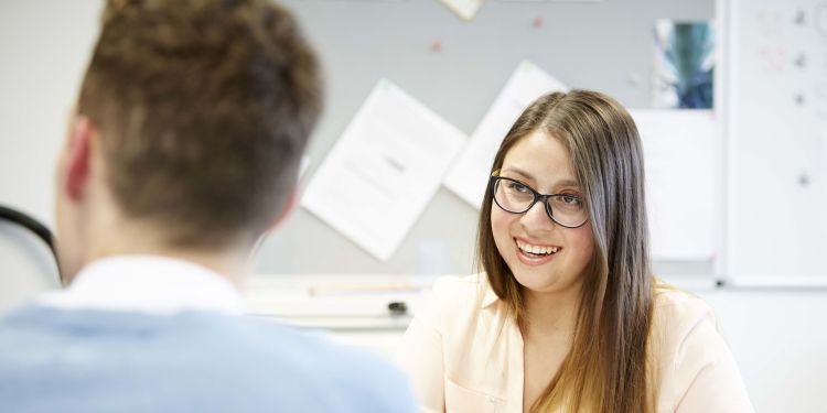 Students pictured talking and smiling in a building on campus