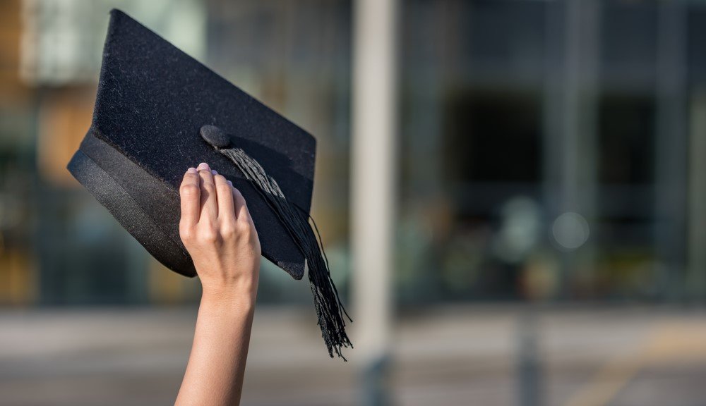 Mortarboard graduation cap held in the air