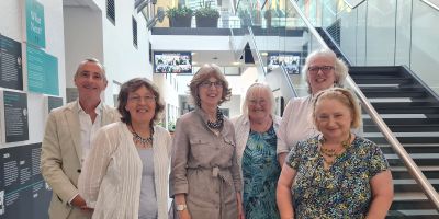Five women and one man smile at the camera in the atrium of the Liberty Building