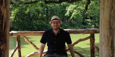 Man sat in front of a body of water and trees
