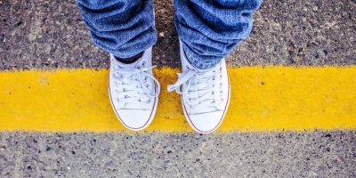 Boy standing on yellow lines at the side of a road