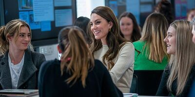 Princess of Wales chats with a small group of university students in a workshop setting.