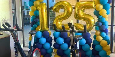 Two stationary bikes in front of gold ballons.