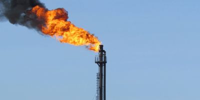 flames and smoke emerging from a chimney on an oil field