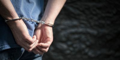a close up photograph of a man's hands cuffed behind his back.