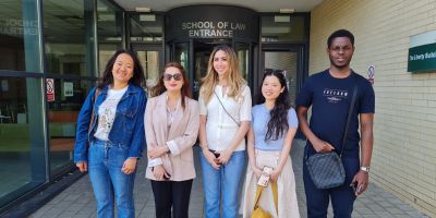 Alumna and students stand in front of the School of Law.
