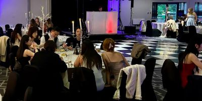 Students and staff seated at tables in front of a dancefloor at the SSP summer ball
