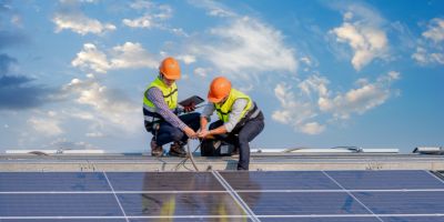 Two workmen fitting solar panels on a roof