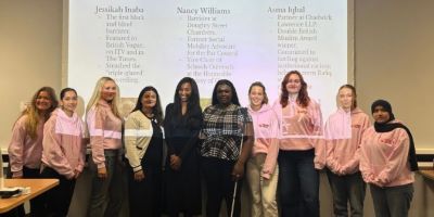 Women Breaking Barriers Committee and three speakers standing in a row in front of a lecture theatre.
