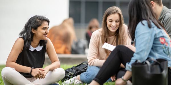 Students talking, sitting on a lawn at the University of Leeds