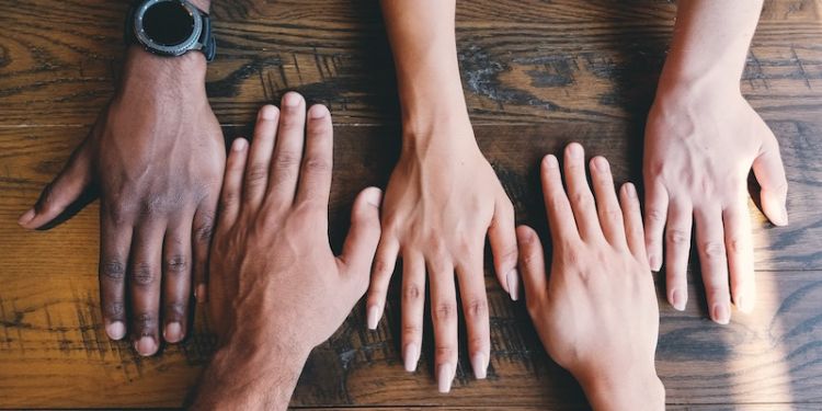 A team's hands on a wooden table