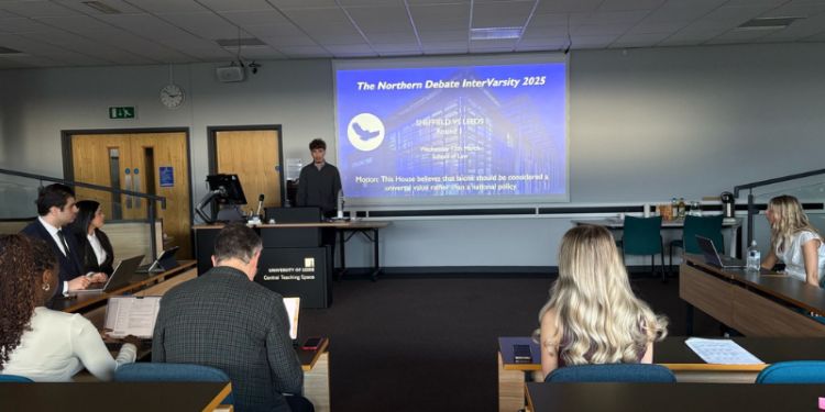 View from the back of a lecture theatre showing people, facing a debaters at the front.