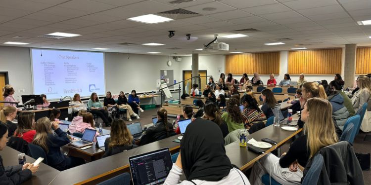 Audience in lecture theatre facing panel of speakers