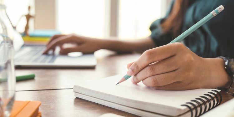 Close up hands with pen writing on notebook